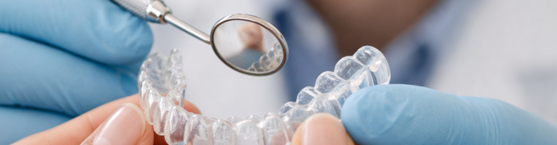 Hands holding clear aligner.